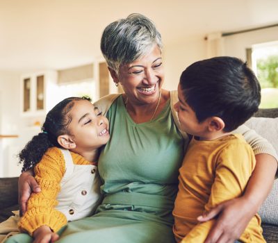 Hug, grandmother or happy kids on a sofa with love enjoying quality bonding time together in family home. Smile, affection or funny senior grandparent with children siblings on house couch laughing.