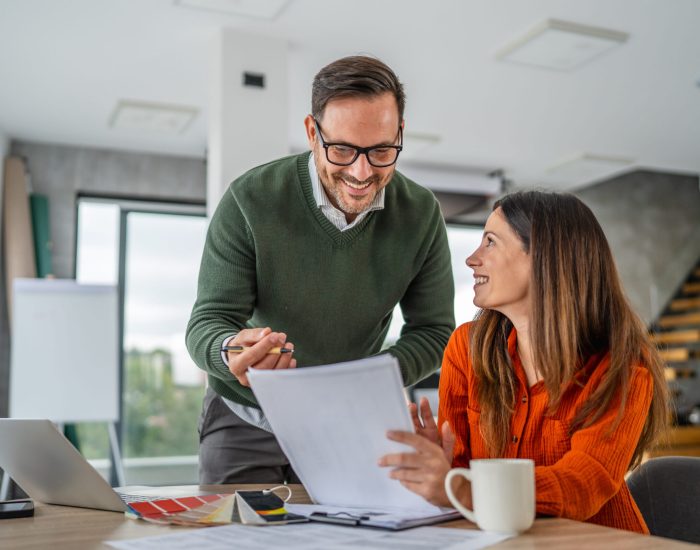 Young couple reviews documents and color swatches on a laptop while planning their home renovation, budgeting and making design decisions together for a new living space
